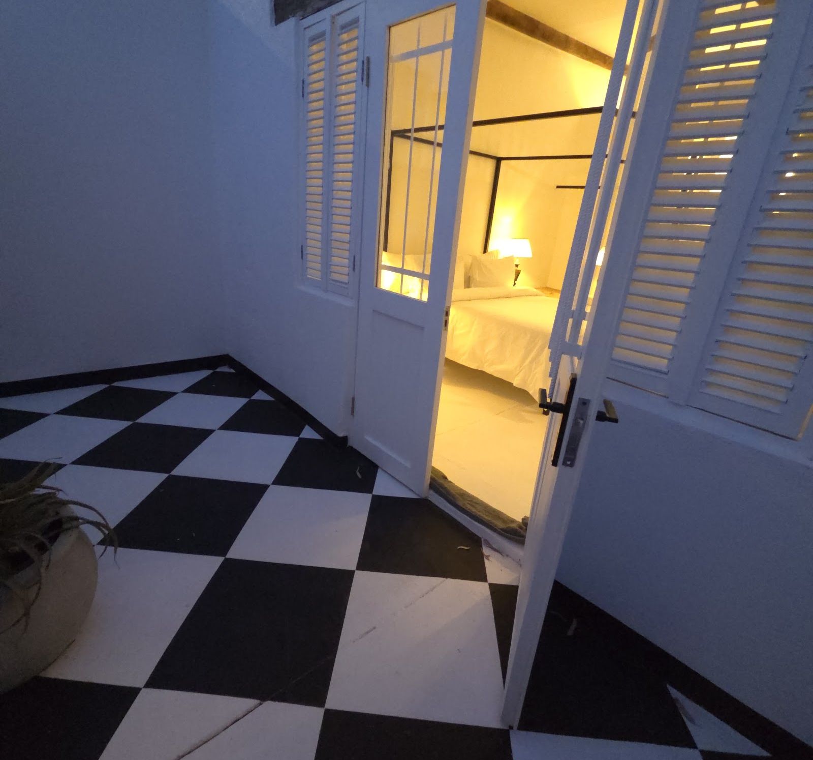 Doors open onto the checkerboard stoep at night